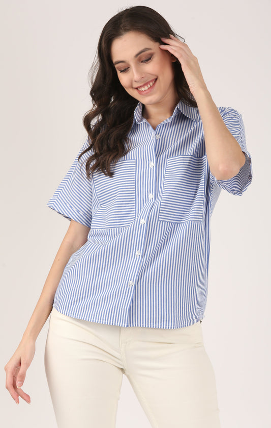 Woman wearing a blue and white striped cotton shirt with short sleeves and oversized front pockets, styled with sandstone jeans